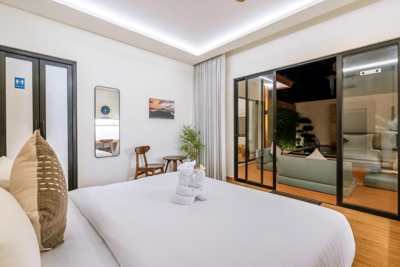 A ground-floor bedroom at night, sliding doors open to the lit deck